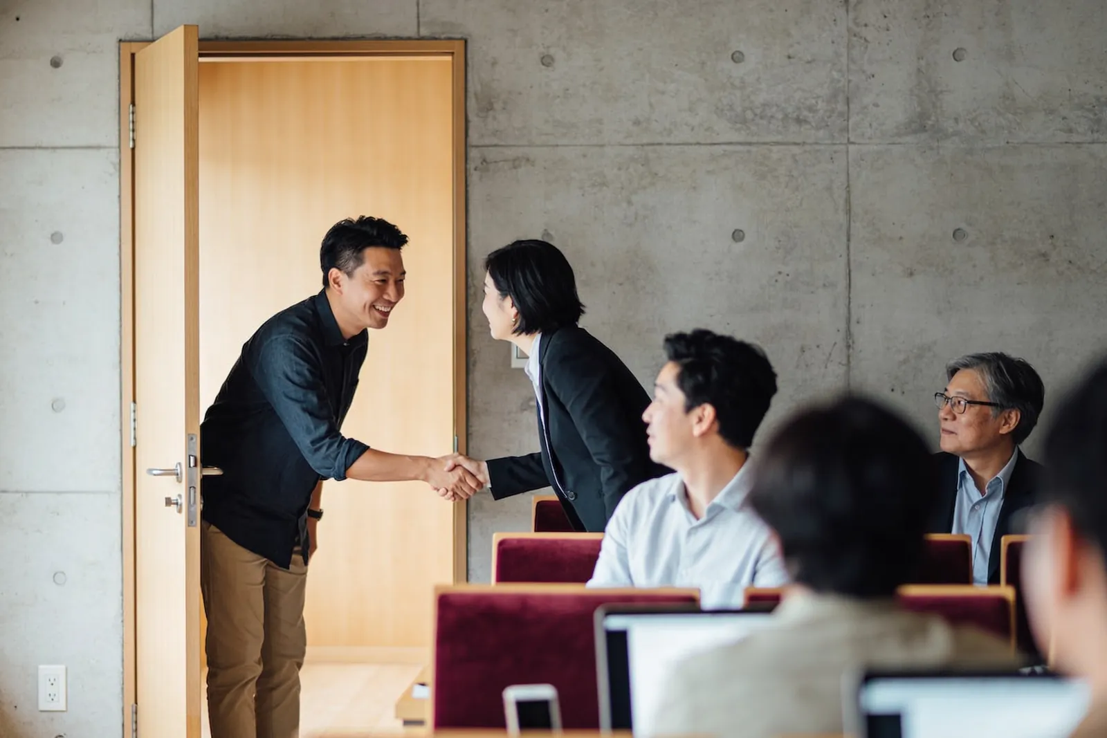 另一堂課開始前,講師在教室門口笑著跟學員握手,其他人已經坐下。