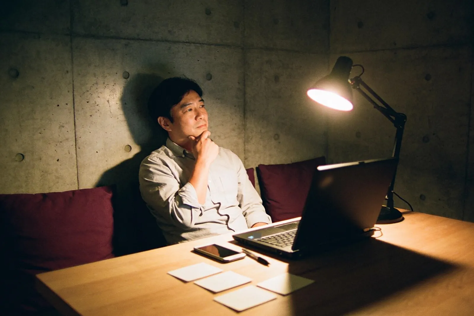 深夜,講師坐在檯燈下,一手托著下巴在想事情,面前的筆電開著,桌上擺著幾張空白卡片。